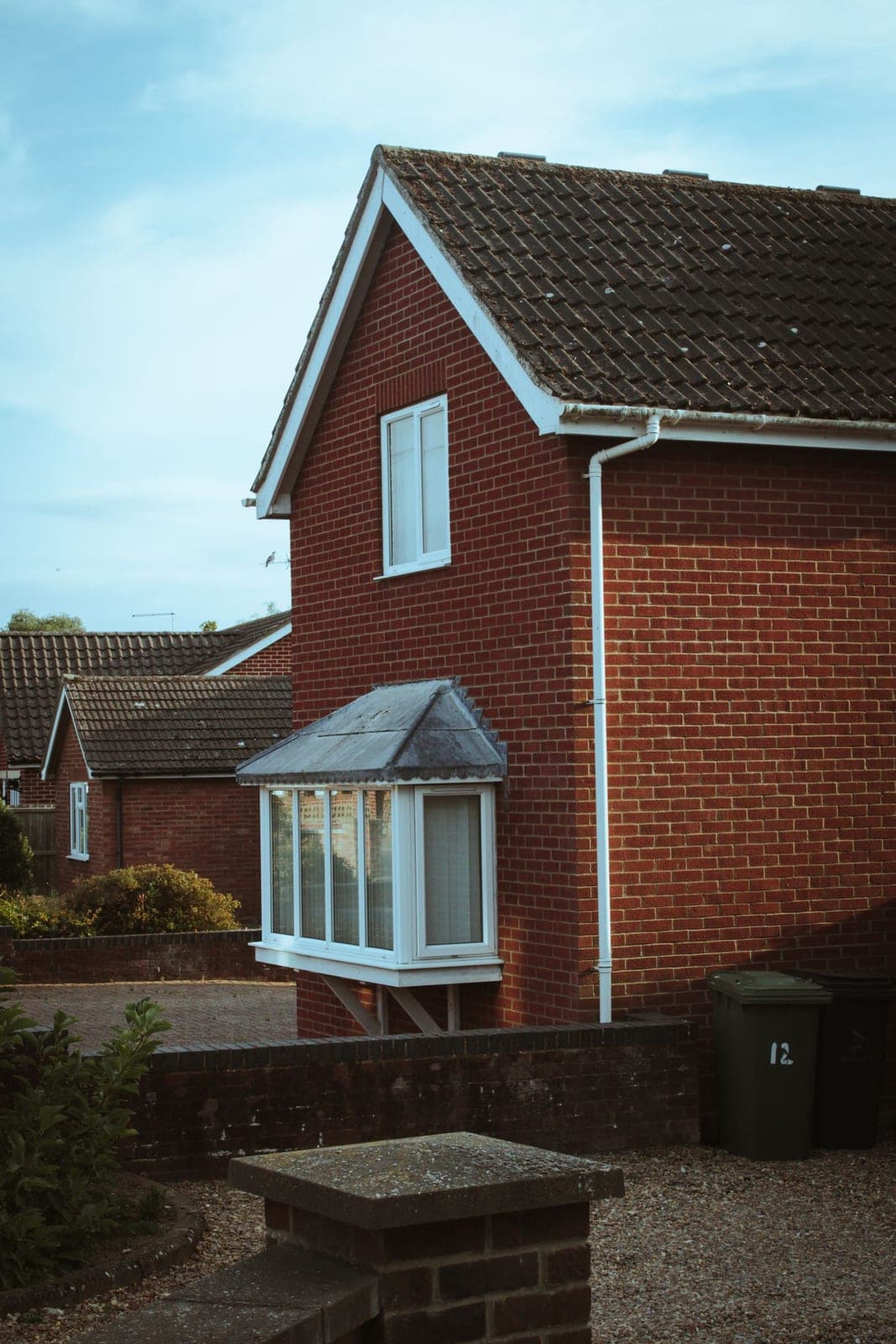 Brick house with a small white bay window bumping out on the ground floor
