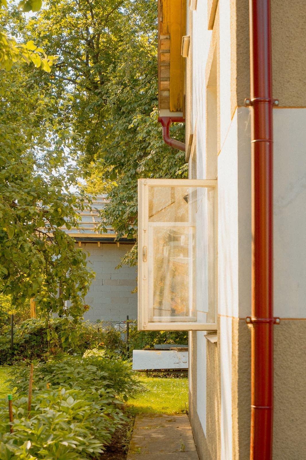 Casement window swung open outward on a light-coloured house