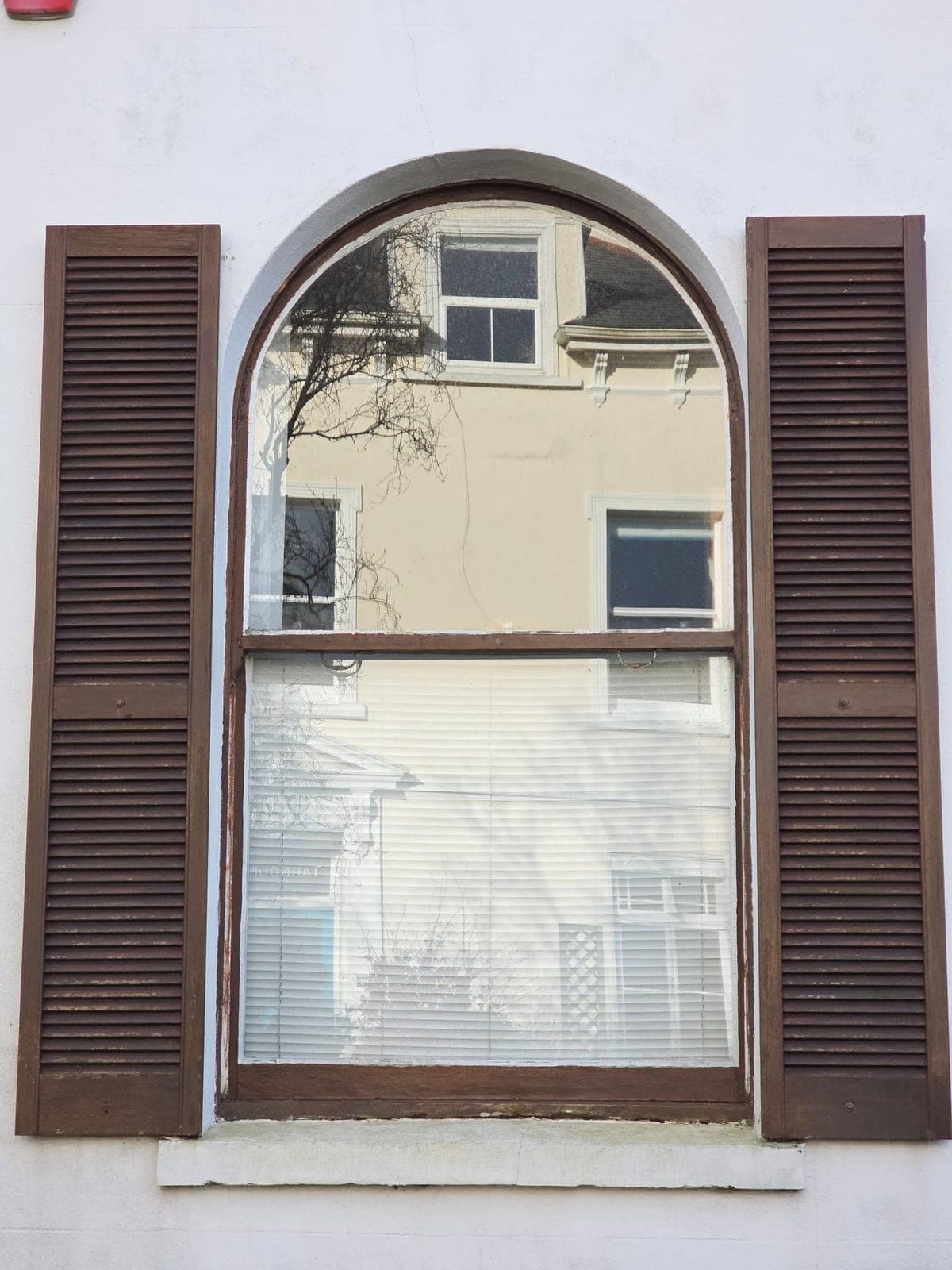 Arched round-top window between dark shutters