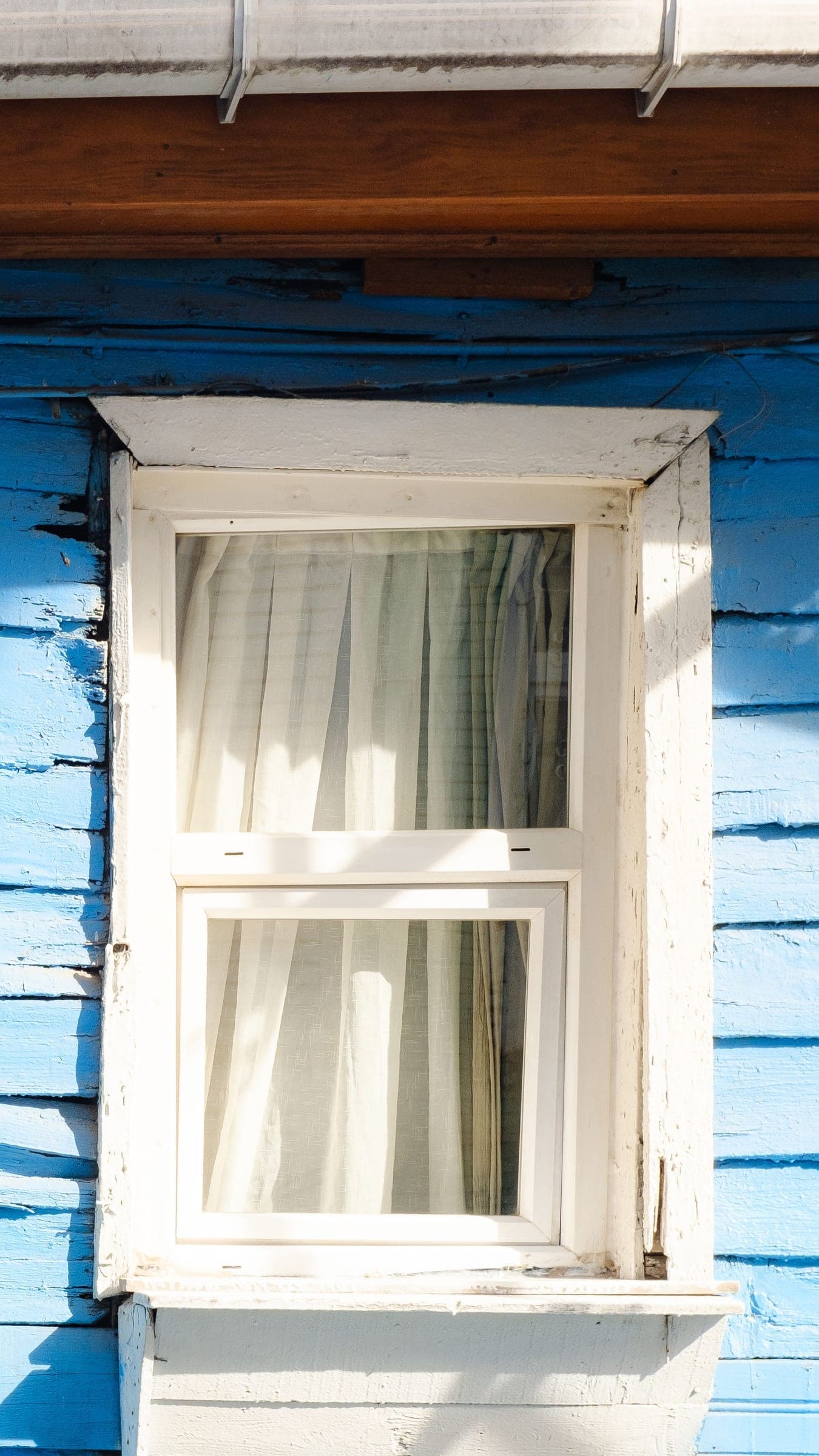 White hung window with trim on pale blue siding