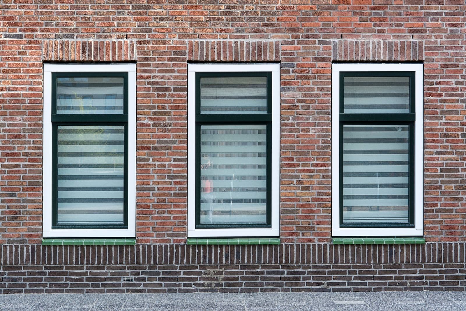 Row of tall windows with dark frames set in a brick wall